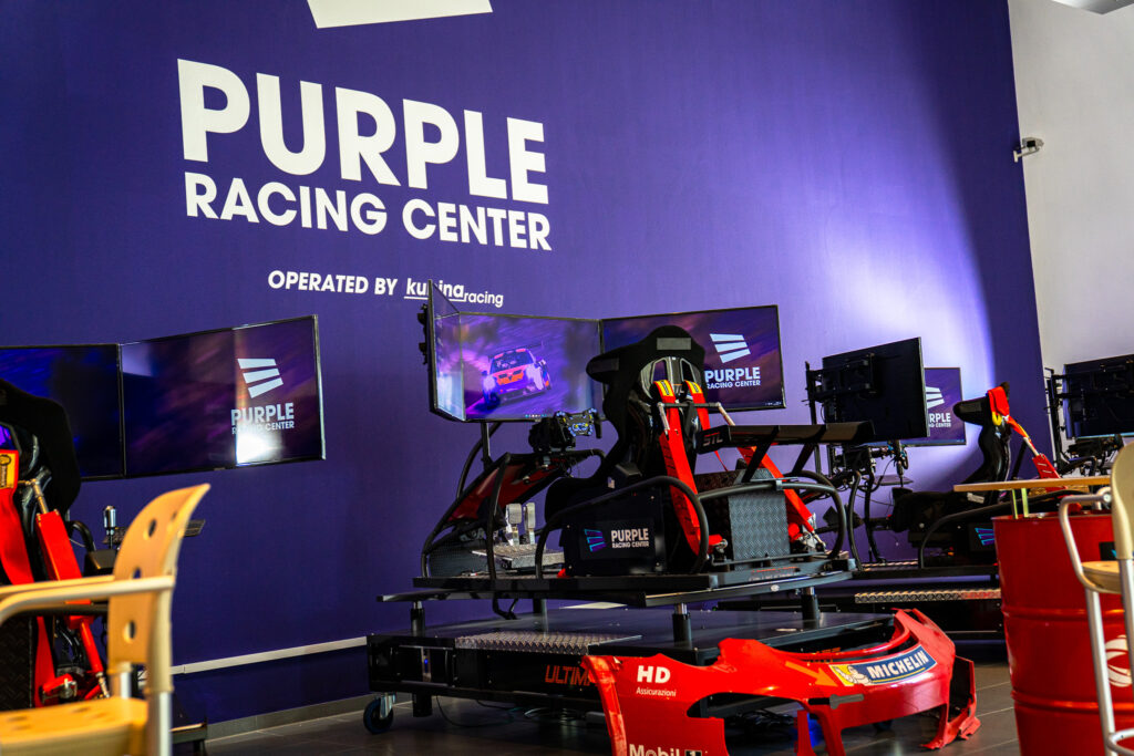 Zwei Rennsimulatoren vor der Purple-Racing-Center-Wand