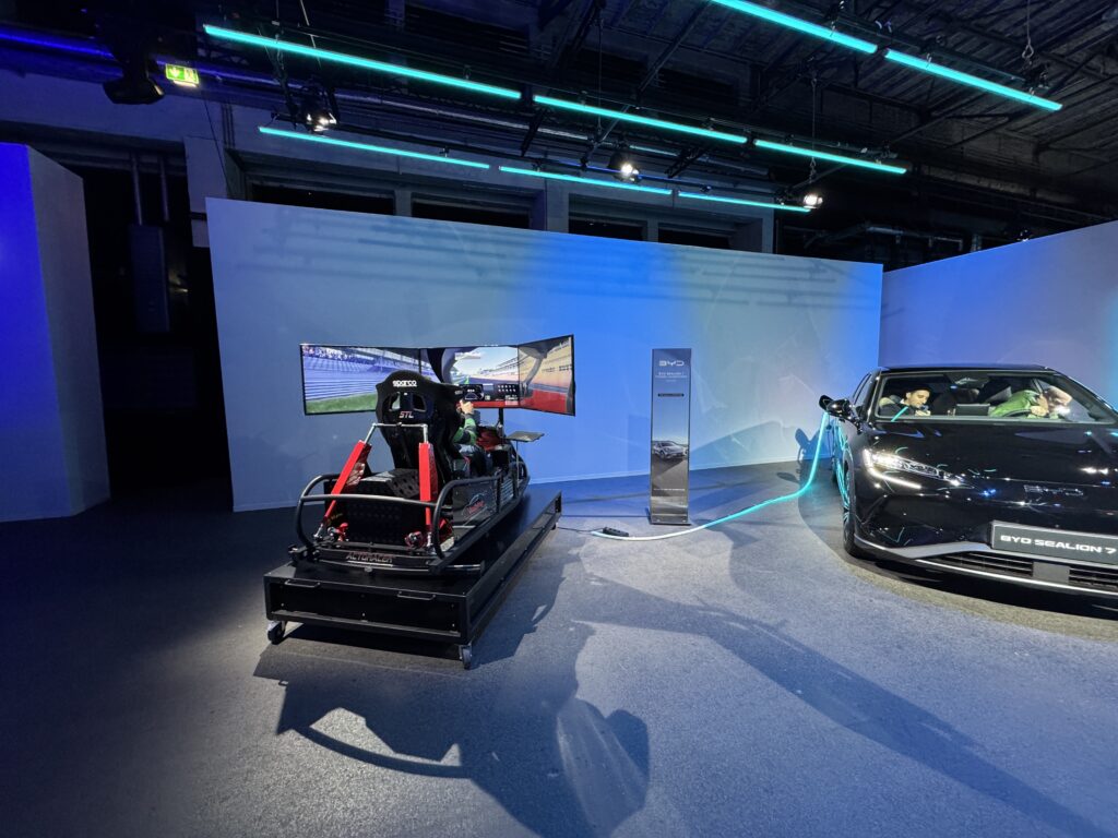 Rennsimulator neben einem Sportwagen bei einer Fahrzeugpräsentation